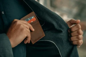 Agente inmobiliario guardando su billetera en el bolsillo de su traje preocupado por sus finanzas personales