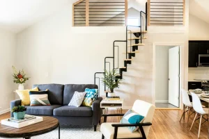 propiedad para invertir en chile, sala con diseño acogedor iluminada y con sofá y escalera a segunda planta