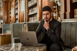 hombre elegante sentado frente a su computador en un café trabajando como broker inmobiliario
