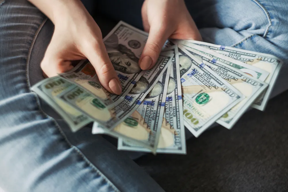 persona sosteniendo un abanico de billetes de 100 dolares