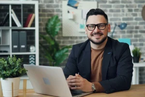 Inversionista sentado frente a su computador revisando un crédito hipotecario feliz por los resultados