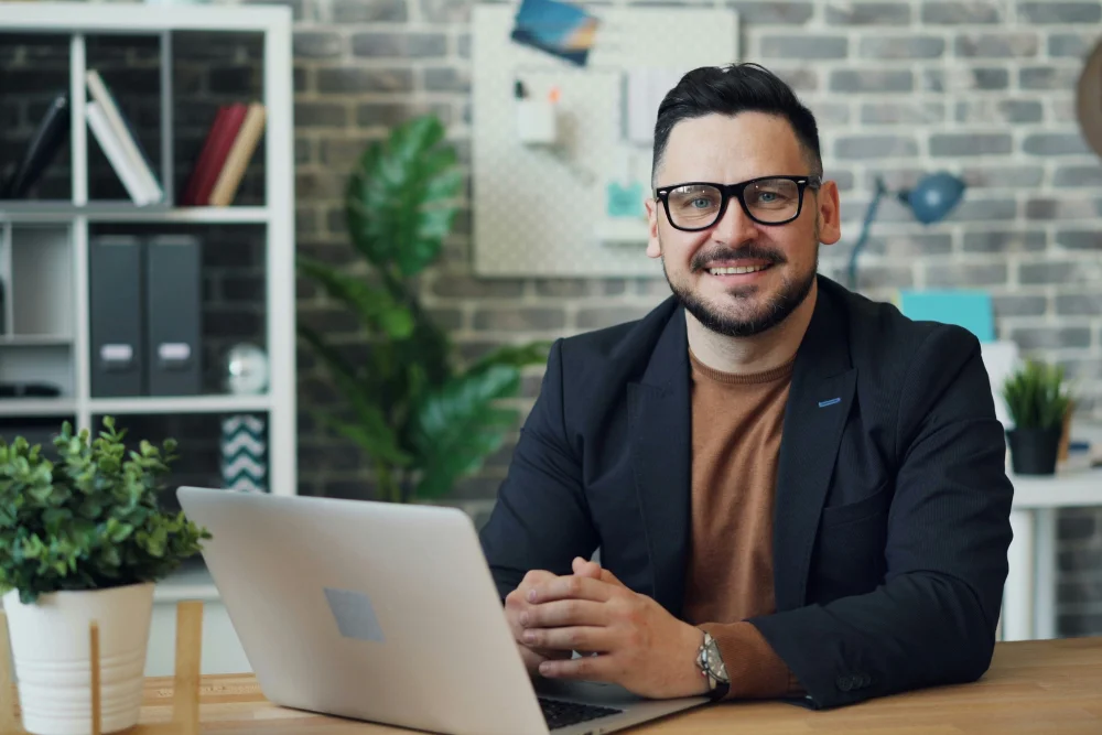 Inversionista sentado frente a su computador revisando un crédito hipotecario feliz por los resultados