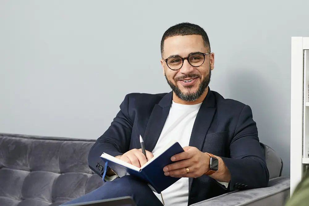 Consultor inmobiliario sentado en el sofá con su libreta sonriendo mostrandote como precalificar credito hipotecario en Chile
