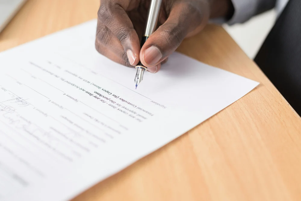 Mano firmando un contrato de refinanciamiento hipotecario para optimizar su inversión