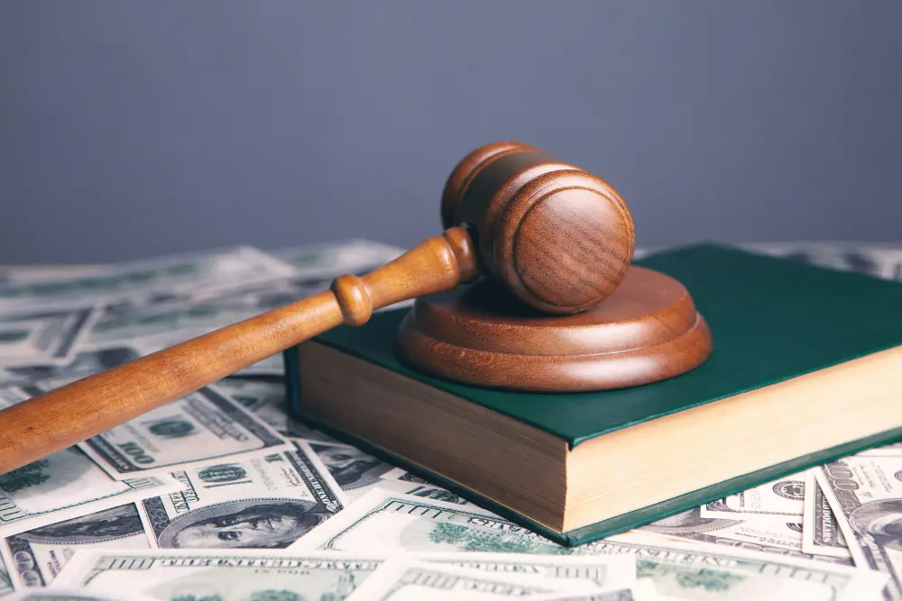 Mazo de madera de juez sobre libro y dinero, haciendo referencia al marco legal y tributario para la inversión inmobiliaria