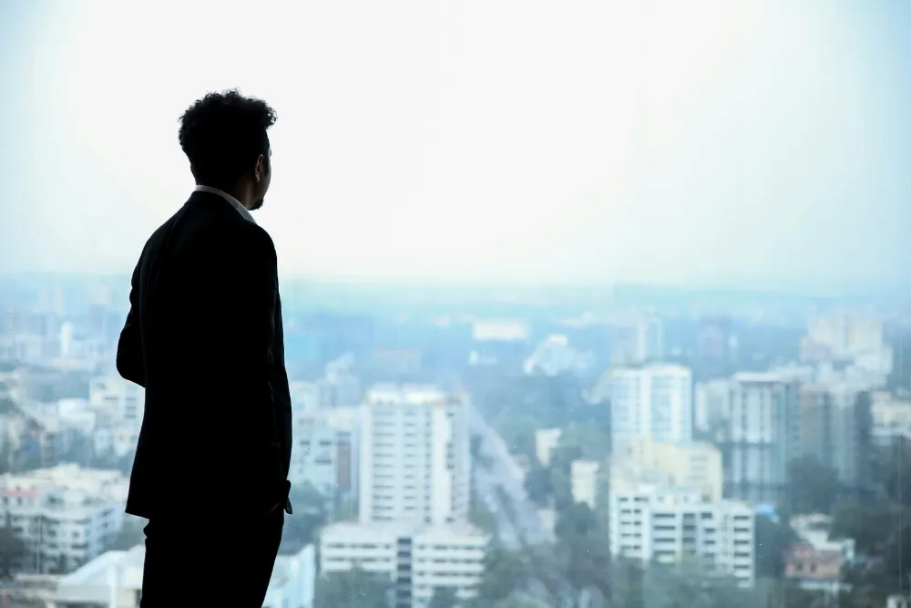 Inversionista mirando la ciudad por la ventana pensando en la optimización de portafolios inmobiliarios